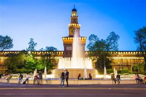 Люди сидят у фонтана перед замком Сфорца (Castello Sforzesco) ночью