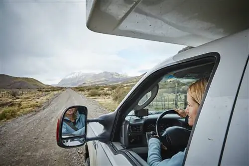Женщина смотрит из окна автофургона, чтобы полюбоваться горным пейзажем.