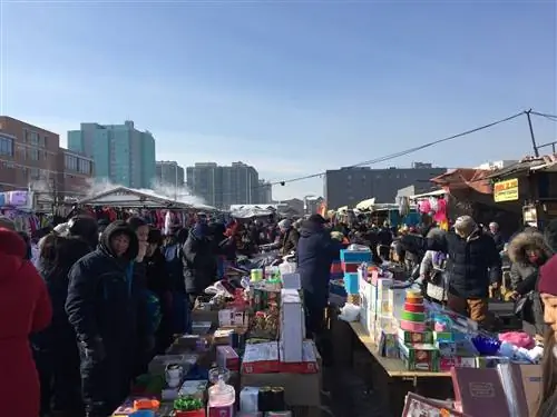Рынок Наран Туул: открытый рынок с рядами столов, заполненных продуктами для продажи и заполненными покупателями в больших пальто под голубым небом.