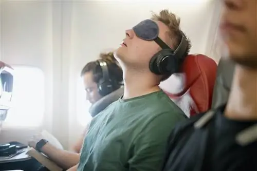 Мужчина в маске для сна спит в самолете