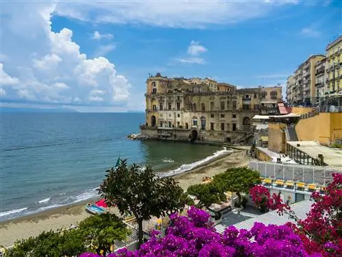 Большой прибрежный дворцовый комплекс с прилегающим песчаным пляжем и спокойным морем.