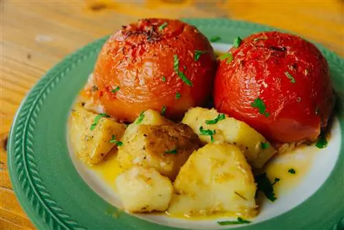 Йемиста, фаршированные помидоры с картофелем, подаваемые на узорчатой синей керамической тарелке