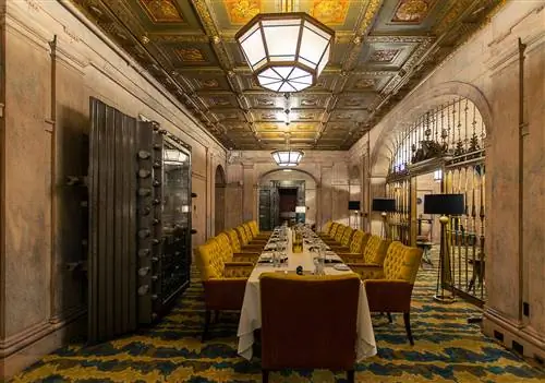 Элегантная приватная столовая в Marble Room Steakhouse & Raw Bar; Комната представляет собой бывший склеп с огромной стальной дверью, богато украшенной решеткой и кессонным потолком.