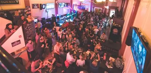 Вид вниз на барную стойку в салоне Wild Eagle Saloon; он битком набит посетителями, которые пьют и перекусывают.