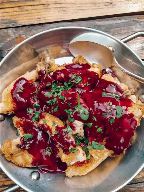 Крупный план жареного цыпленка в красном соусе с рубленой зеленью