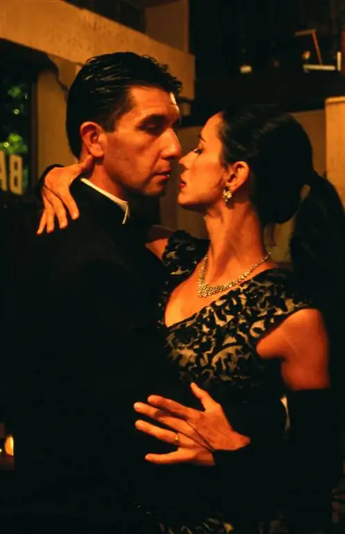 Мужчина и женщина прижимаются друг к другу, танцуя аргентинское танго в Буэнос-Айресе.