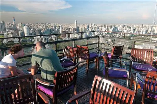 Дневной вид на крышу Moon Bar, люди сидят за столом на фоне раскинувшегося городского пейзажа