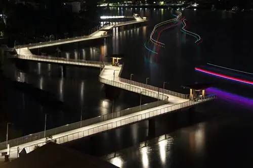 Зигзагообразная тропа набережной Нью-Фарм ярко освещена ночью и контрастирует с черной водой реки Брисбен.