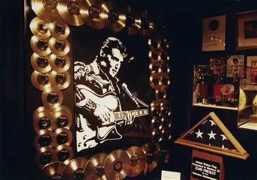 Золотые пластинки служат обрамлением для черно-белого портрета Элвиса Пресли, а также для сложенного американского флага и других памятных вещей в Грейсленде.