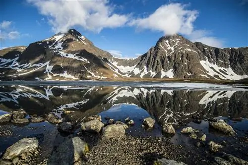 Заснеженные горы под голубым небом с берегом озера на переднем плане