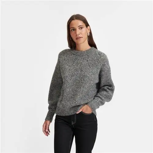 модель в большом свитере Everlane с круглым вырезом из альпаки темно-серого цвета и черных брюках.