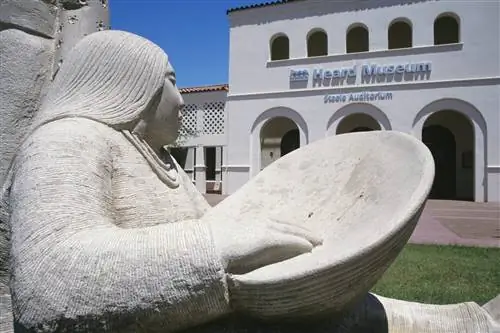 Скульптура индейской женщины с миской стоит возле музея Херда с белыми стенами в Фениксе, Аризона, США.