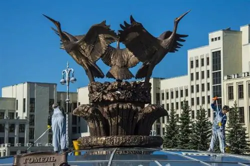 Женщина чистит гигантскую статую птицы на вершине стеклянного купола на площади Независимости в Минске.