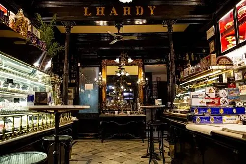 Роскошный интерьер Lhardy с позолоченными светильниками, панелями из темного дерева и полом, выложенным белой плиткой.