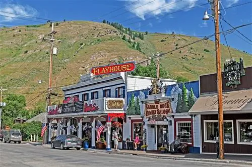 Внешний вид Jackson Hole Playhouse - это старый салон в западном стиле. На заднем плане виднеется большой зеленый холм.