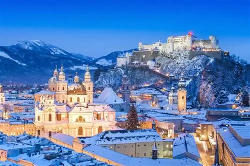 Зальцбургский собор и Festung Hohensalzburg покрыты снегом и светятся под вечерними уличными фонарями