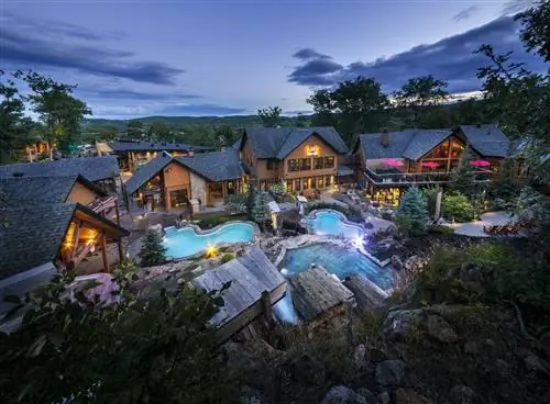 Вид с воздуха на Nordik Spa Nature - коричневые дома вокруг 3 бассейнов Вид с воздуха на Nordik Spa Nature - коричневые дома вокруг 3 бассейнов