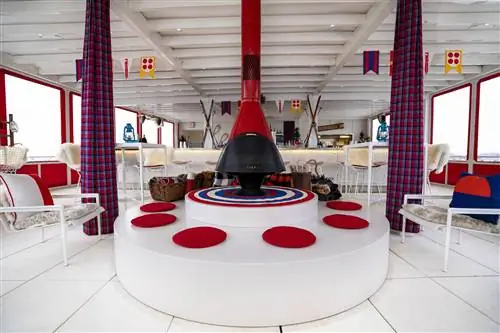 TWA Hotel Runway Chalet в интерьере бара у бассейна - красный камин на круглом белом основании с красными подушками