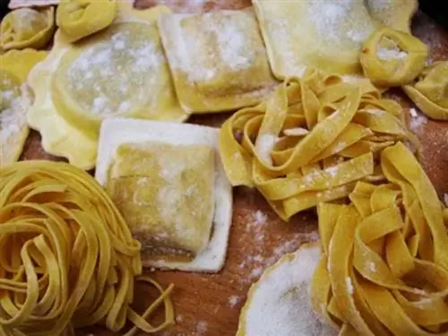 Свежая итальянская паста, посыпанная мукой, тальятелле справа.
