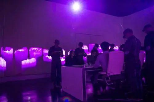 Сотрудники ресторана «Ультрафиолет» обслуживают своих гостей в обеденном зале в Шанхае, освещенном фиолетовым светом.