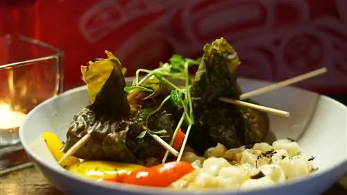 Пара зеленых пельменей лежит в тарелке с овощами; Местная еда