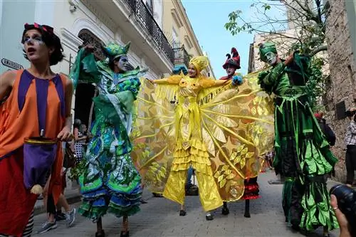 Группа ходулистов направляется по старой Гаване в замысловатых ярких костюмах; Годовщина Гаваны