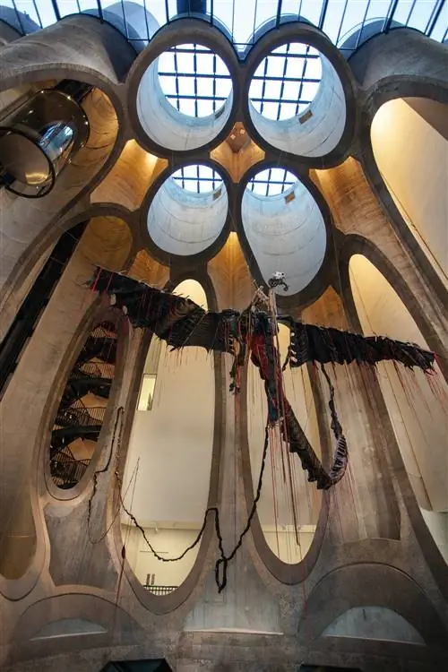 Произведение искусства, похожее на птеродактиля, висит в огромном атриуме Zeitz MOCAA; атриум был высечен из штабеля столбчатых бункеров, каждый из которых был обрезан по-разному (некоторые выглядят как круги, парящие вверху, в то время как у других просто удалены части сторон, которые напоминают овальные окна).