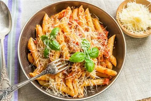 Паста All'Arrabbiata, пенне с томатным соусом и базиликом и сыром пармезан на деревенском деревянном столе с льняной салфеткой