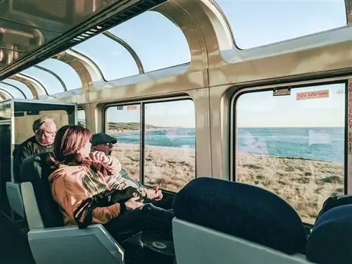 Трое пассажиров сидят в вагоне-салоне на маршруте Coast Starlight, который проходит через Пасо-Роблес. Один пожилой джентльмен зевает, любуясь пейзажем. Женщина с короткими темными волосами просто отвернулась от камеры. Третий мужчина сидит позади зевающего джентльмена и задумчиво смотрит в окно.