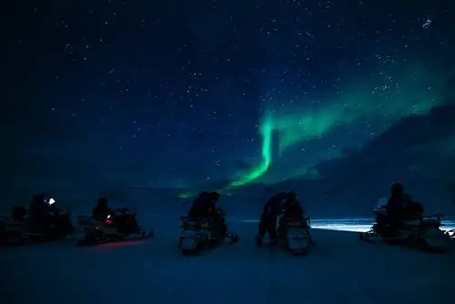 Люди на электросамокатах на фоне северного сияния