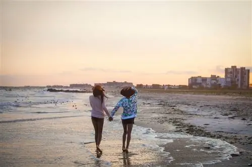 Две женщины держатся за руки и идут по воде