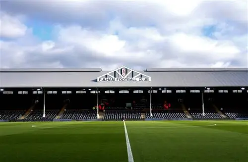 Футбольное поле Craven Cottage в слегка пасмурный день. Футбольное поле и трибуны пусты, а яркая зеленая трава выглядит идеально.