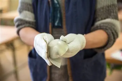 Крупный план рук в перчатках, шлифующих медную чашку для саке.