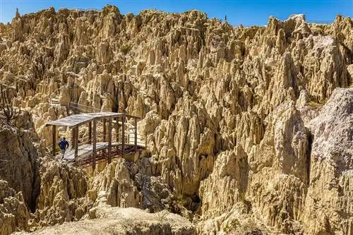 Человек переходит по деревянному мосту среди зубчатых геологических образований в Валье-де-ла-Луна. Ла-Пас, Боливия.