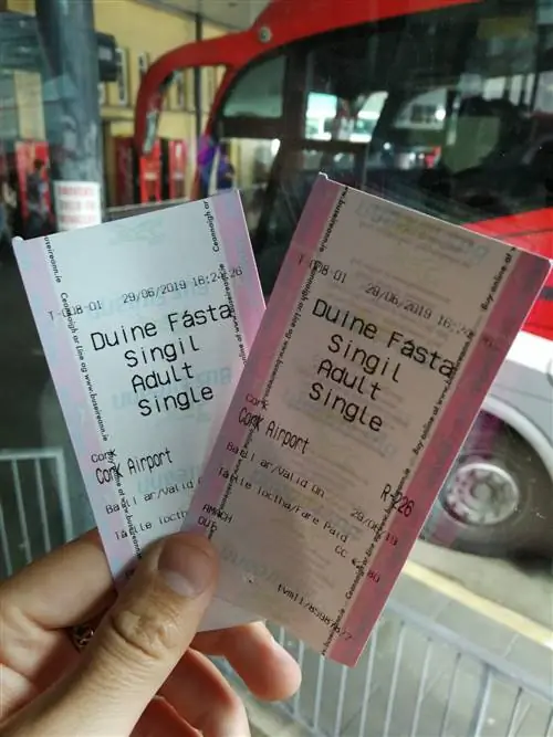 Рука Кристины держит два билета на автобус на фоне тренера.