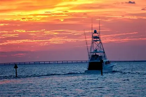 Большая рыбацкая лодка выходит в открытое море во время заката в Дестине, Флорида; холостяк