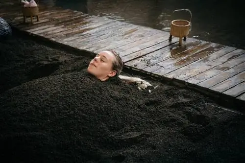 Женщина, принимающая теплую песчаную ванну в Такэгава-Онсэн