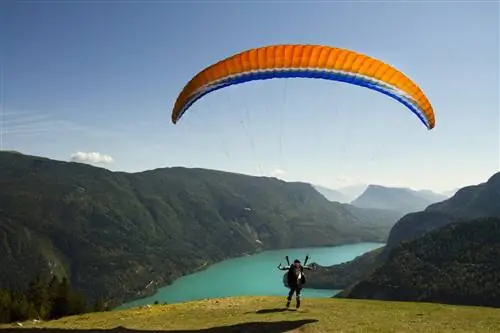 Параплан взлетает над бирюзовыми водами озера Мольвено.