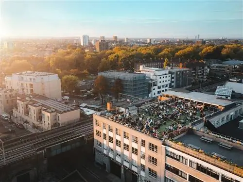Вид с воздуха на Netil360, на крыше четырехэтажного современного здания; деревья парка видны дальше, а горизонт города еще дальше.