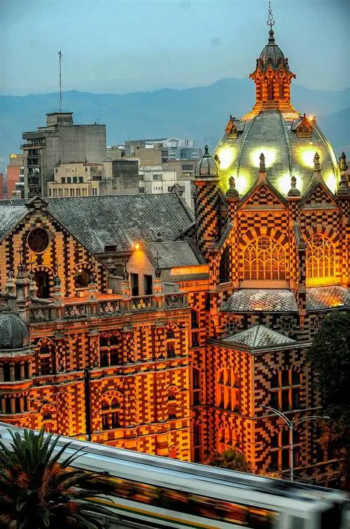 Сложный дворец из черного и белого кирпича, освещенный оранжевыми огнями на закате.