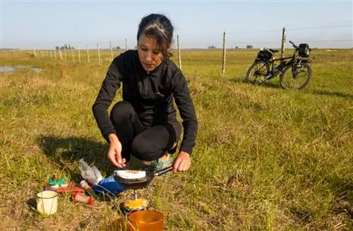 Женщина ездит на велосипеде и готовит себе еду.