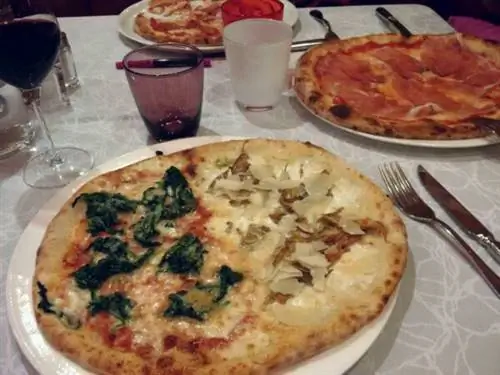 Семейная пицца, состоящая из половины овощной пиццы со светлой пшеницей Камут, копченой ветчиной и детской пиццы с сосисками.