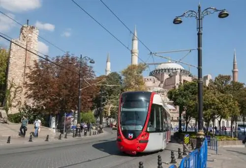 Современный трамвай проезжает по главной улице старого города.