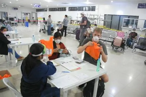 Застрявшие туристы получают сумку MalasaKIT от члена команды DOT8 A перед посадкой на рейс Cebu Pacific для обезумевших иностранных туристов.