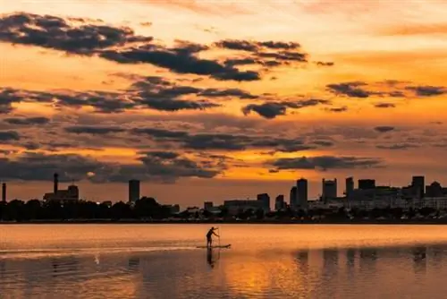 Пейзажная фотография силуэта человека на лодке возле городских зданий, сделанная @alexiby через Unsplash
