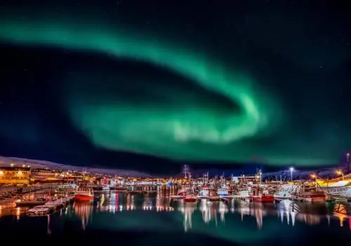 Фил Вулли/Shutterstock. Красочные лодки в гавани, освещенные северным сиянием