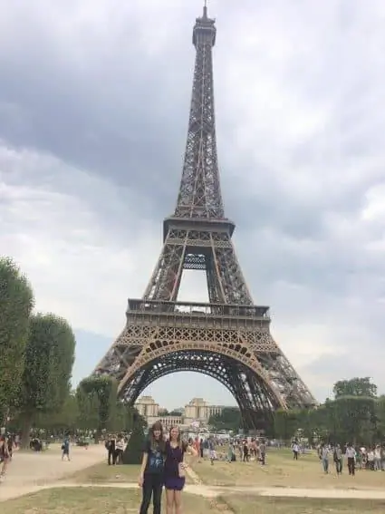 Сара Эдди (слева) и сестра Бекка Эдди перед Эйфелевой башней со смартфоном в руке.