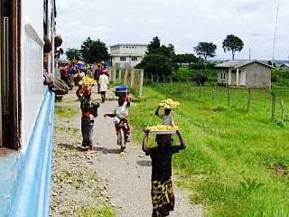 Женщины, продающие бананы и чапати, бегут рядом с поездом Тазара.