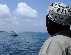 Мужчина наблюдает за дау с парома из Дар-эс-Салама на Занзибар