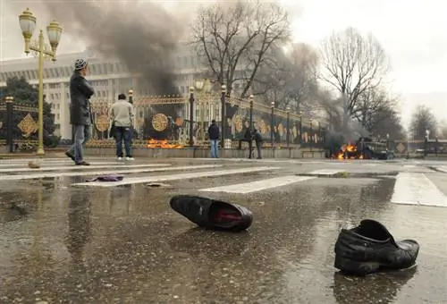 Пара обуви, оставленная на улице после того, как тело увезли в Бишкеке, Кыргызстан, апрель 2010 года. На заднем плане - горящий грузовик во время революции.